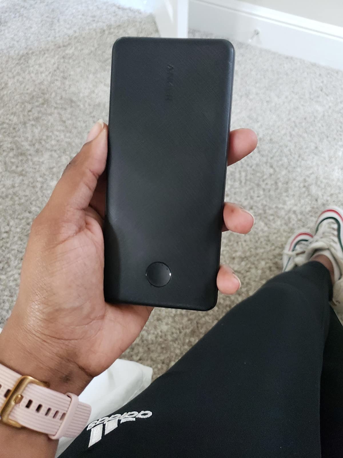 reviewer holding the slim black portable charger