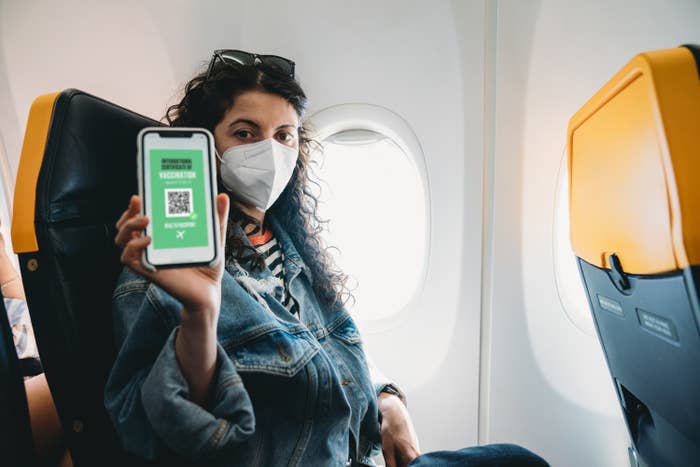 A masked airline passenger displaying her digital passport on her cellphone