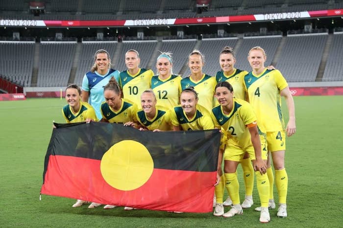 The Matildas pose for a team photo with the Aboriginal flag prior toΒ their match