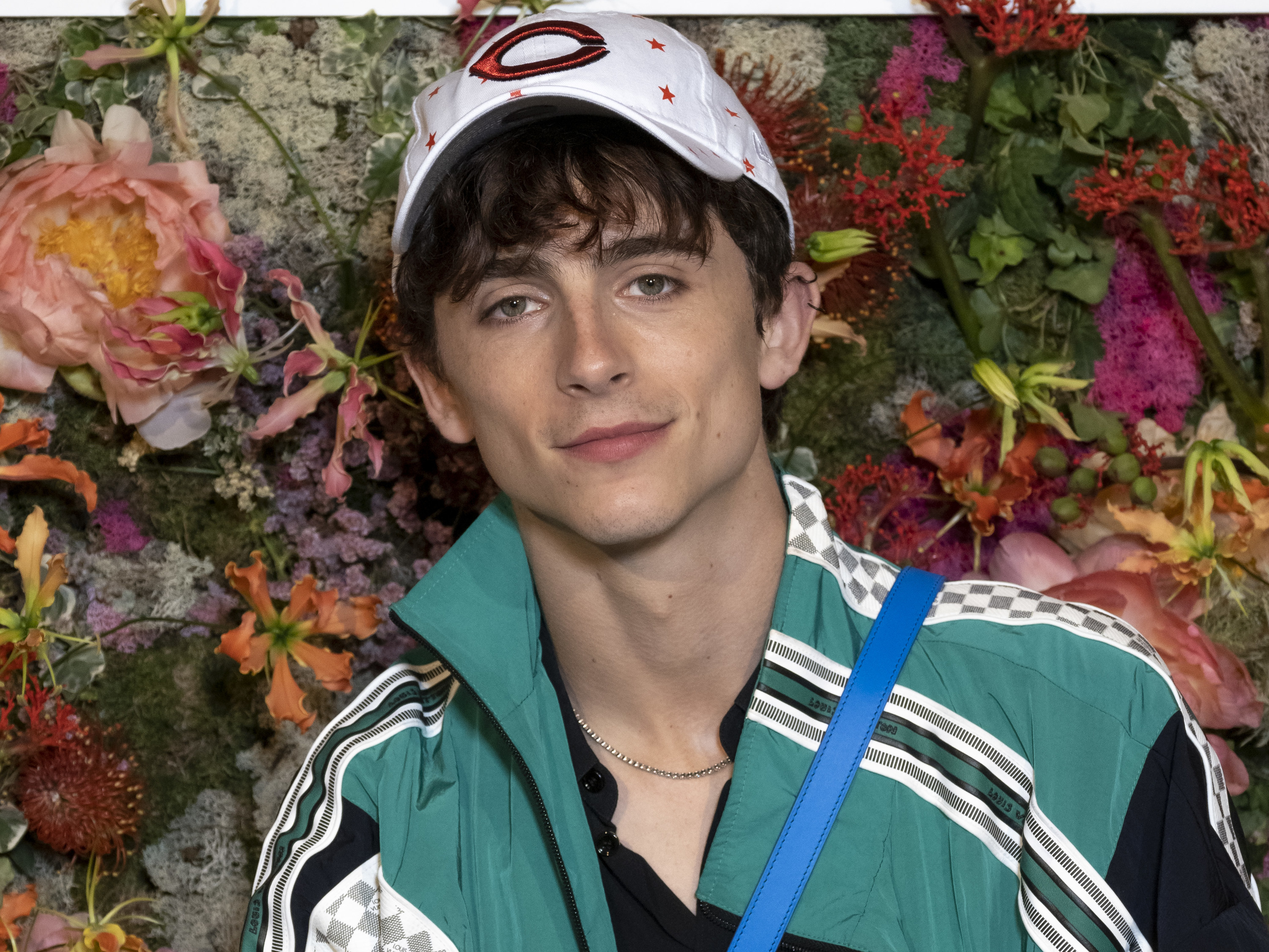 Timothée Chalamet is pictured standing in front of a floral backdrop at the Cannes Film Festival