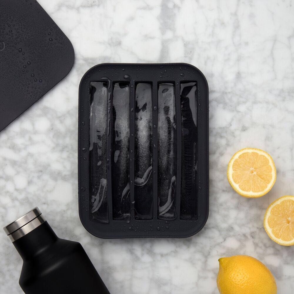 A flatlay of the ice tray filled with extra-long ice sticks, surrounded by fresh lemons