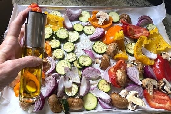 reviewer spraying vegetables with the oil spray