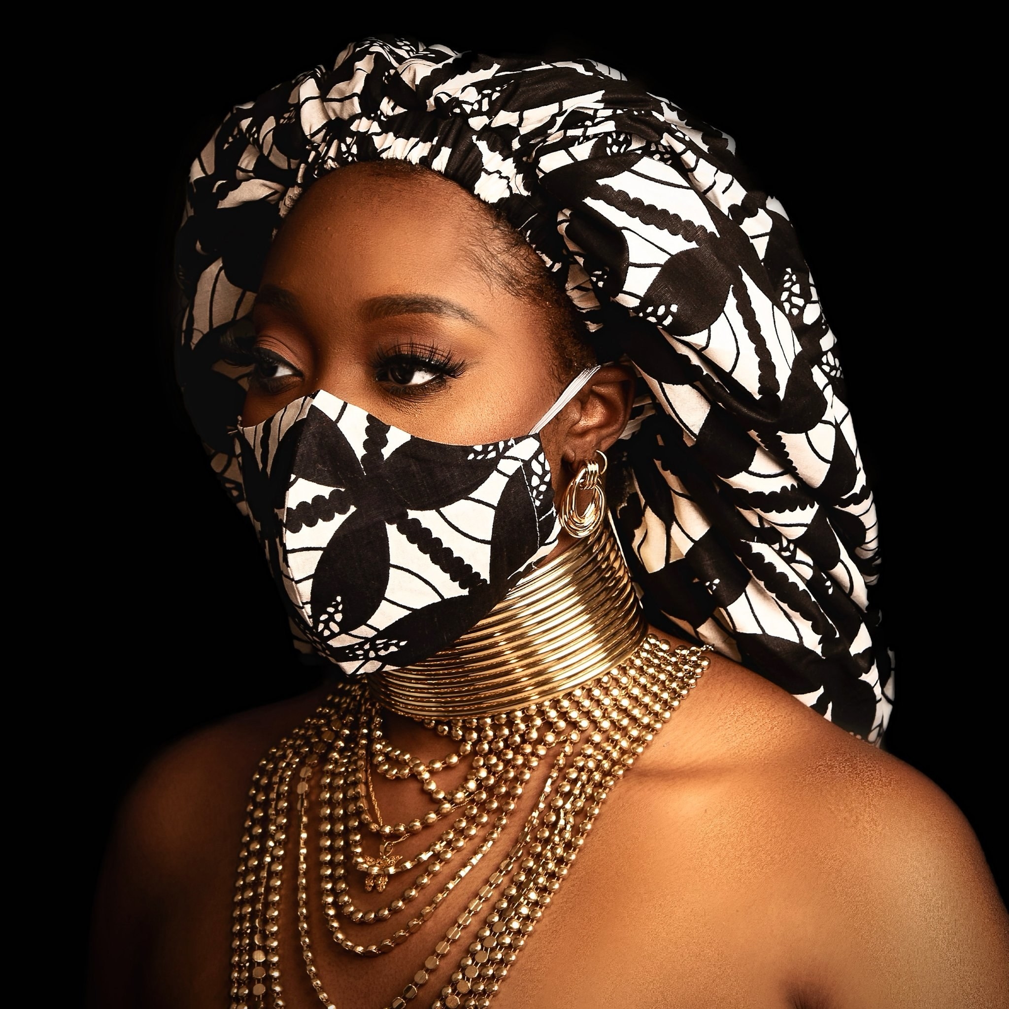 a model wearing the black and white naira print silk bonnet with matching face mask