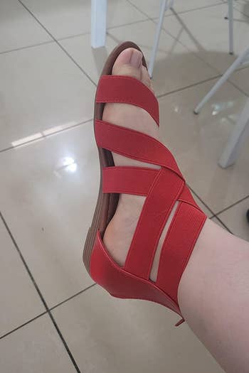 a profile view of a reviewer's feet in the red sandals 