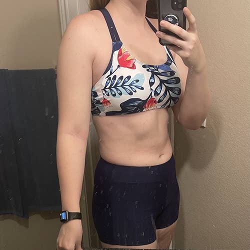 reviewer showing the blue floral sports bra bikini top and shorts suit
