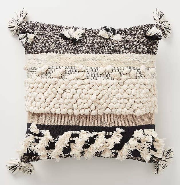 A black/beige/cream, boho-style throw pillow with textured details