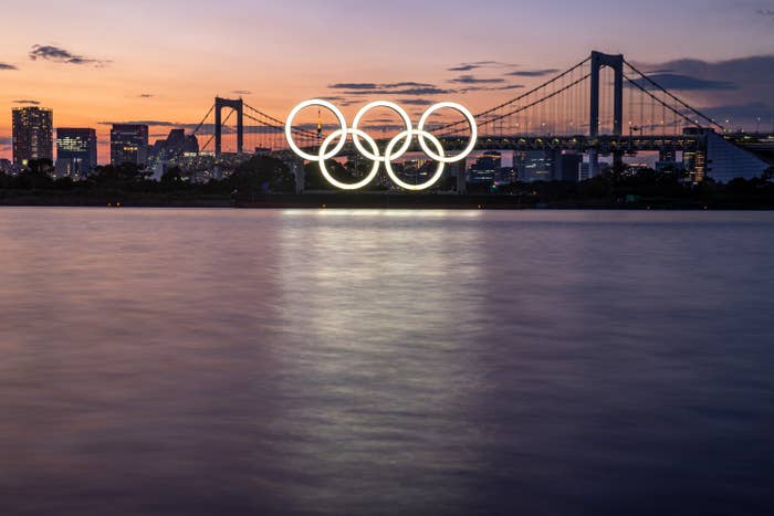 The Olympic rings lit on the side of a bridge