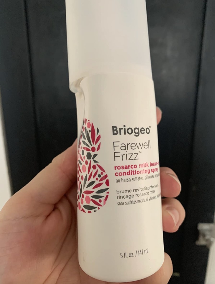 the Briogeo farewell frizz leave-in conditioning spray being held by a reviewer
