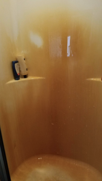 reviewer pic of shower surround with tons of rusty stains on it