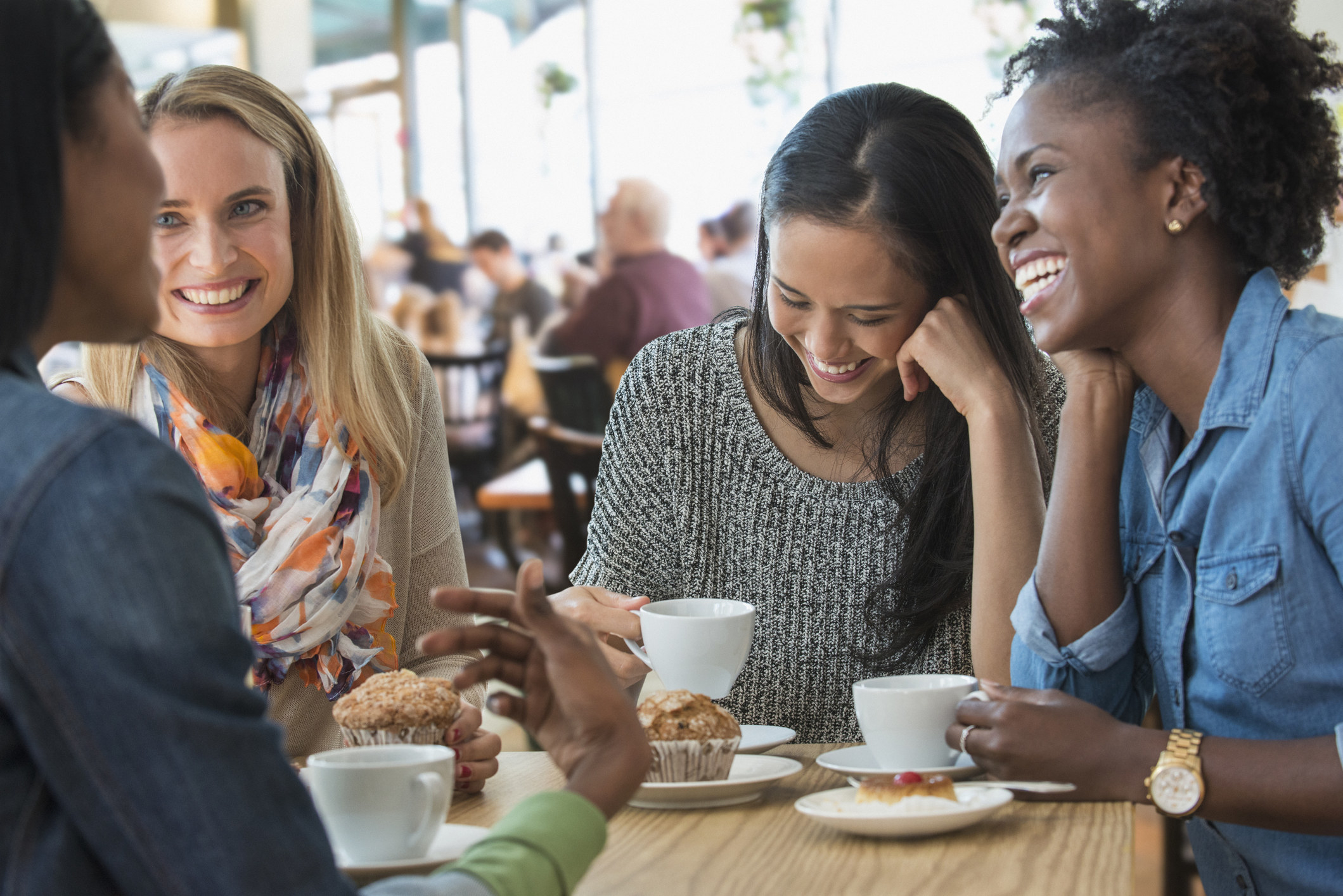 Four women having coffee together and laughing