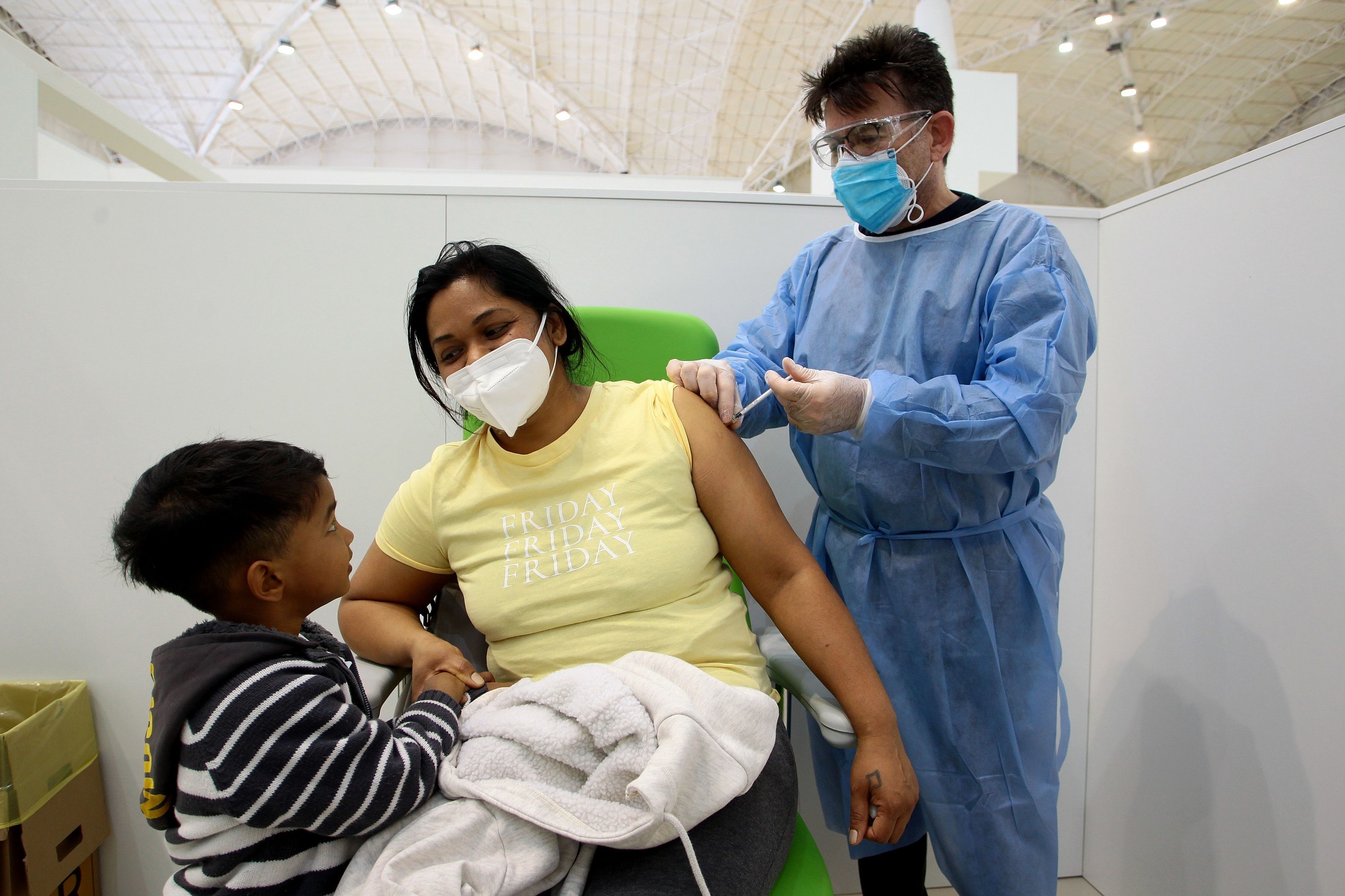 Adult receives vaccine while holding child&#x27;s hand