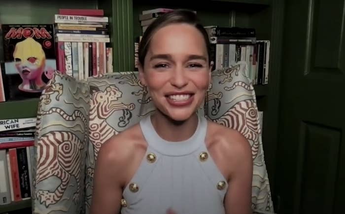 Emilia grins in a screenshot from her interview where she is sitting in a library in her home