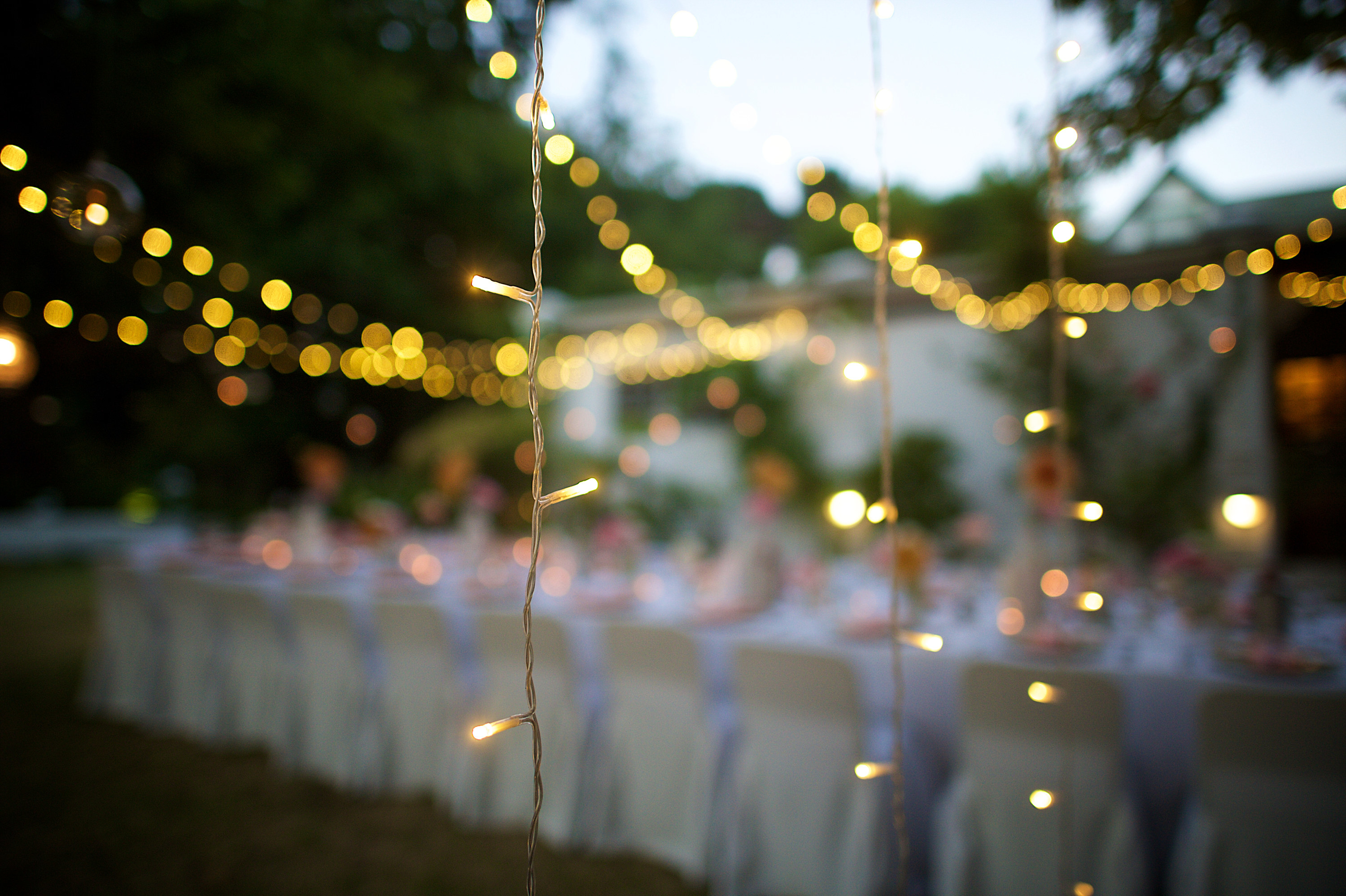 A blurry photo of a wedding table with fairy lights strung over it