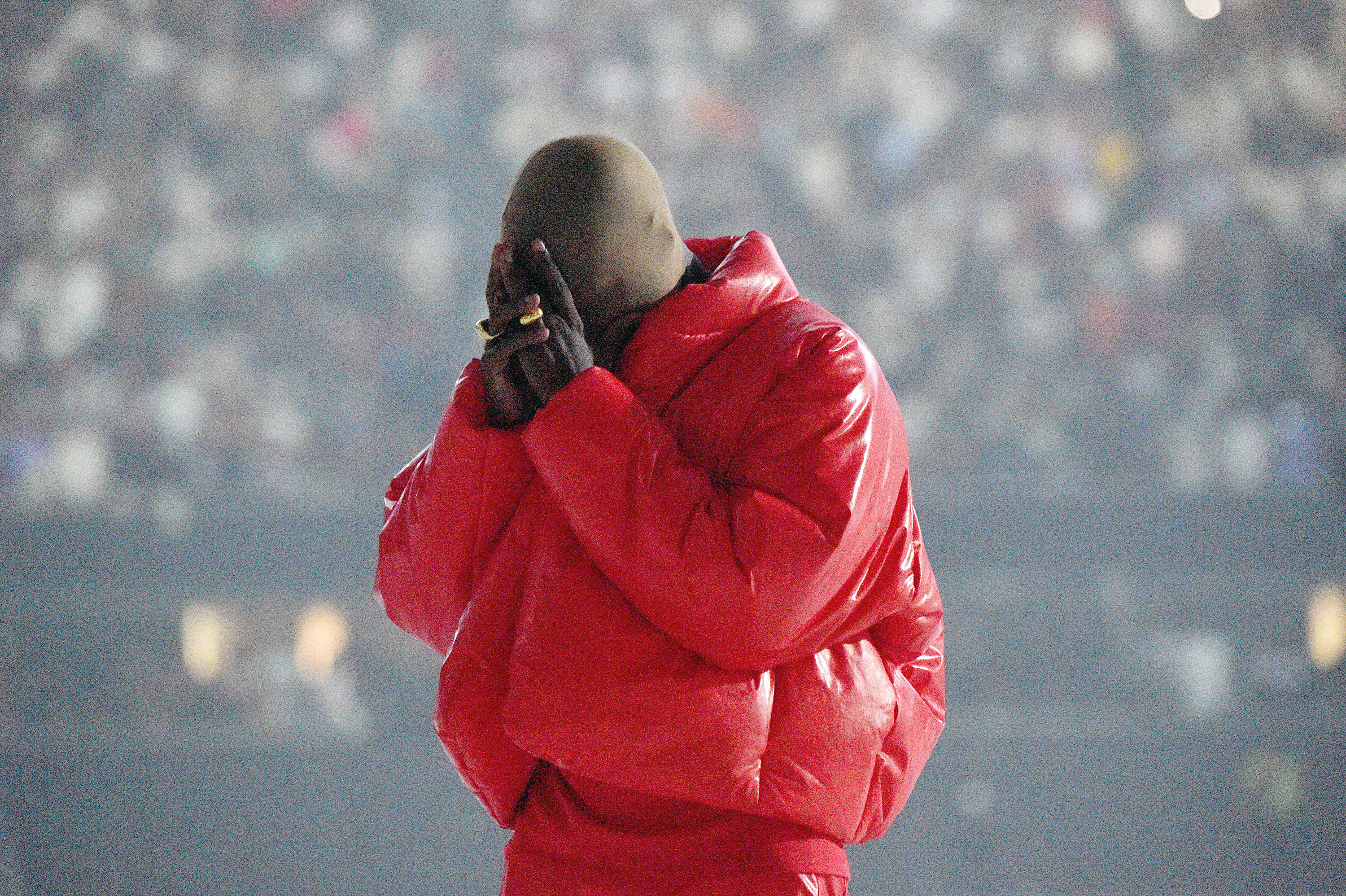 Kanye West is pictured wearing a red puffer coat at his Donda album listening event