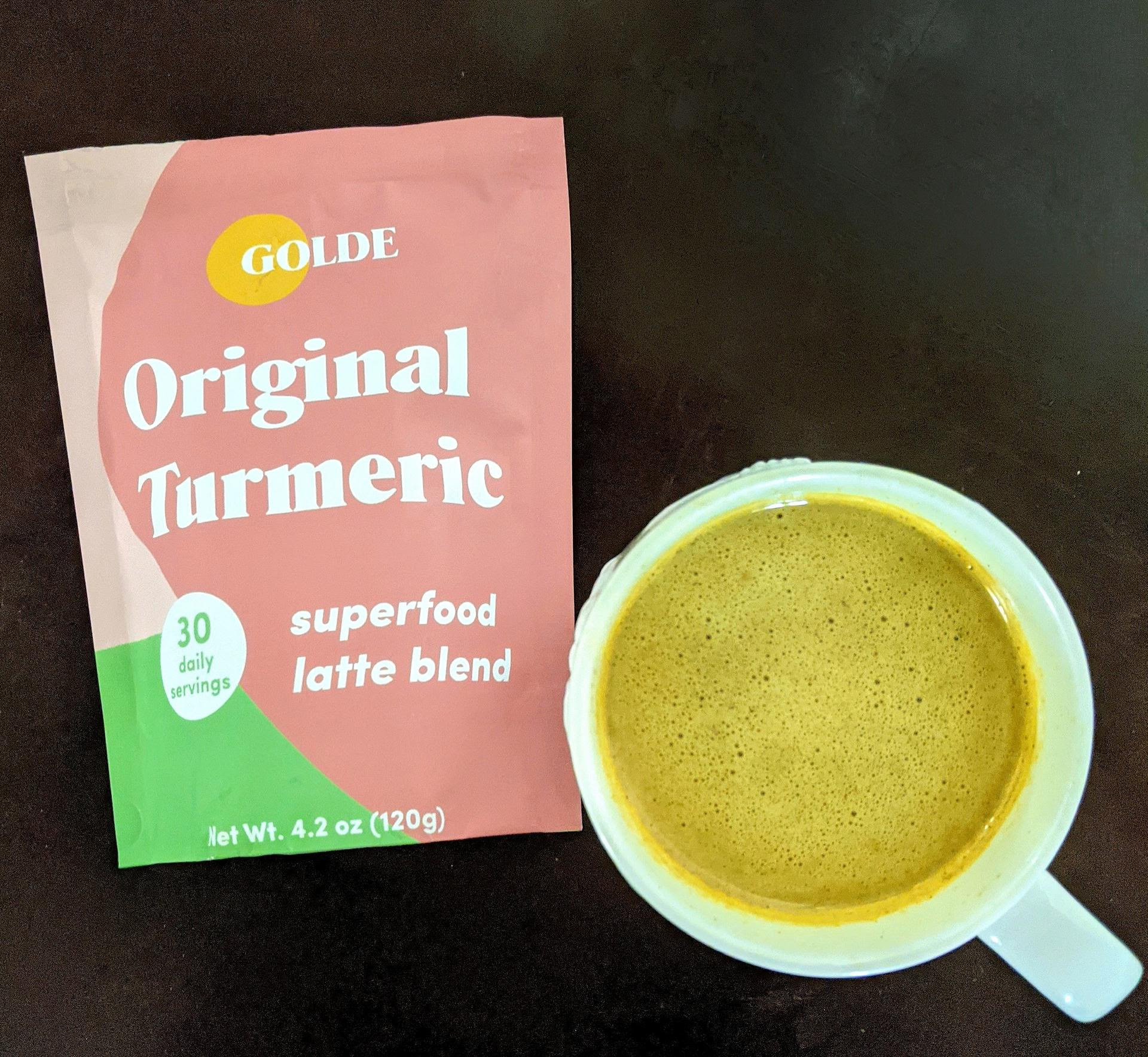 buzzfeed editor&#x27;s yellow tumeric latte next to the package of latte mix