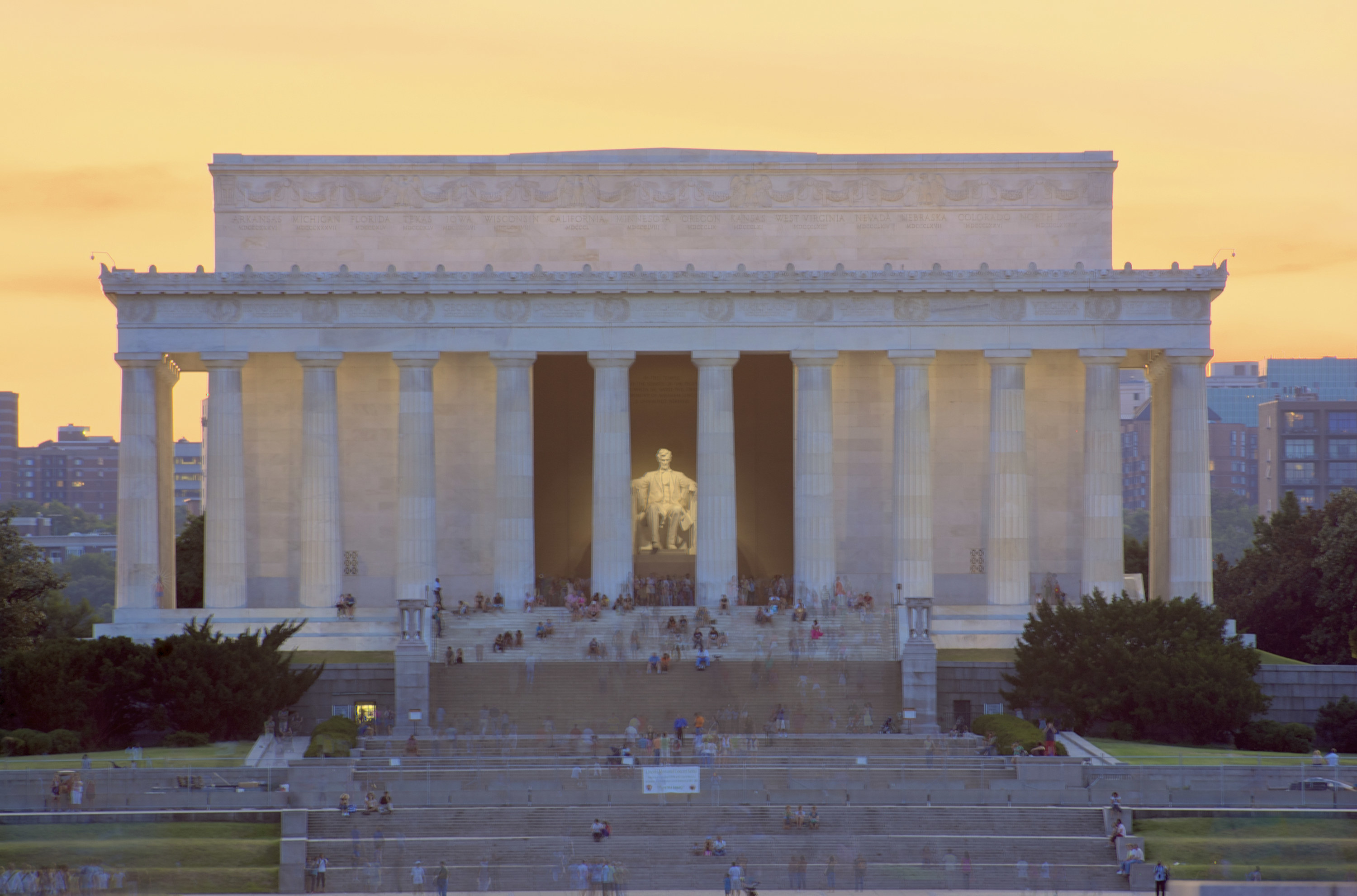 Lincoln Memorial at sunset with many people sitting and standing on its steps