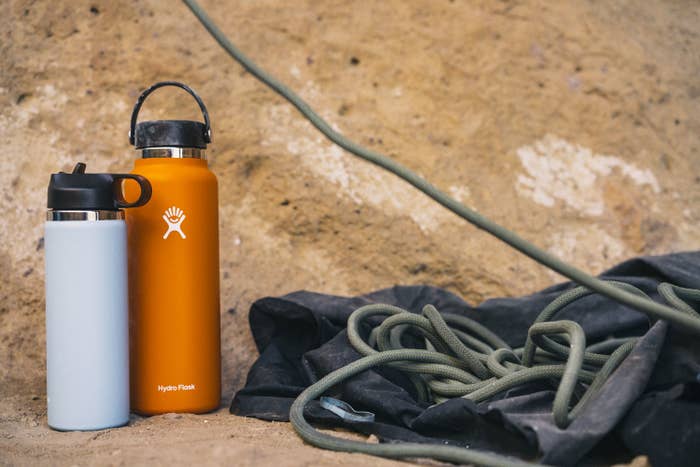 Two Hydro Flask water bottles near the base of a boulder