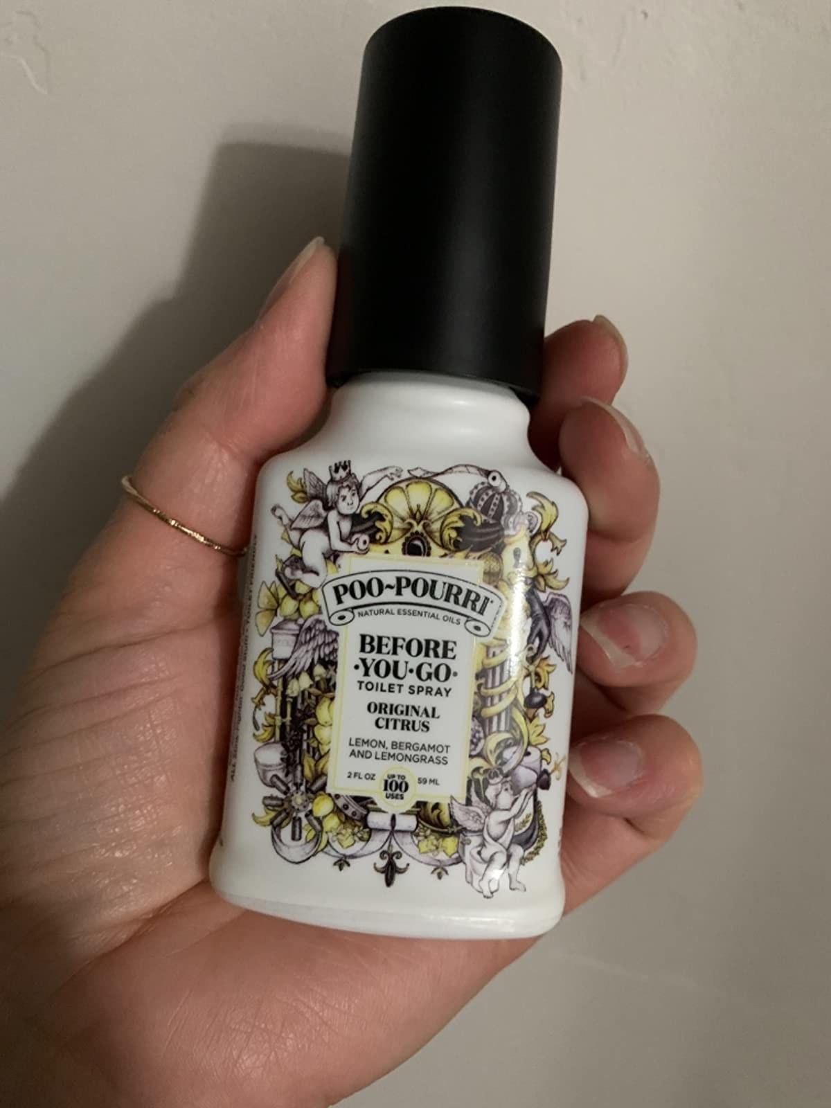 image of a reviewer's hand holding the 2 oz bottle of citrus poo-pourri