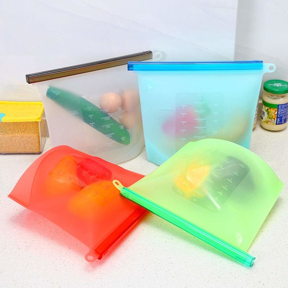 4 ziplock silicone bags with food items on a countertop