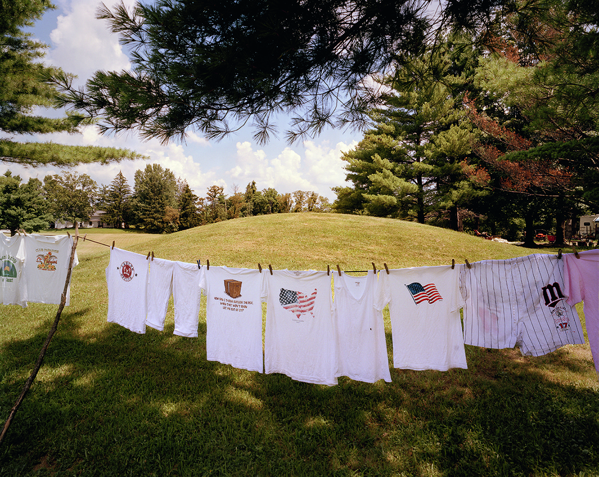 Laundry, mainly white shirts showing images including the US flag, hangs on a line