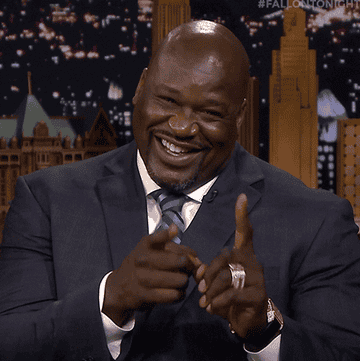 Shaq smiles and wags his pointer fingers