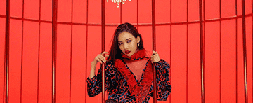 Sunmi smirks and looks into the camera while trapped behind the bars of a large birdcage