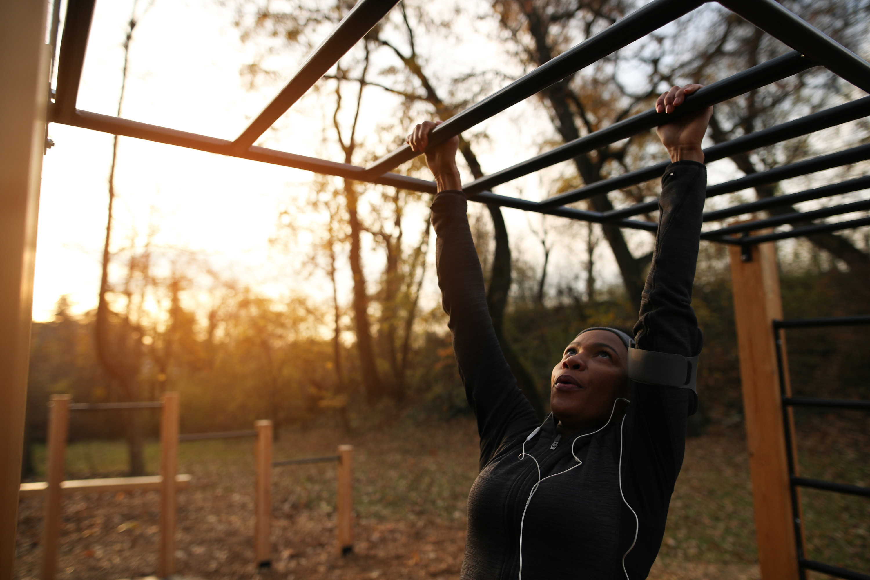 a woman dangling from some bars in a park