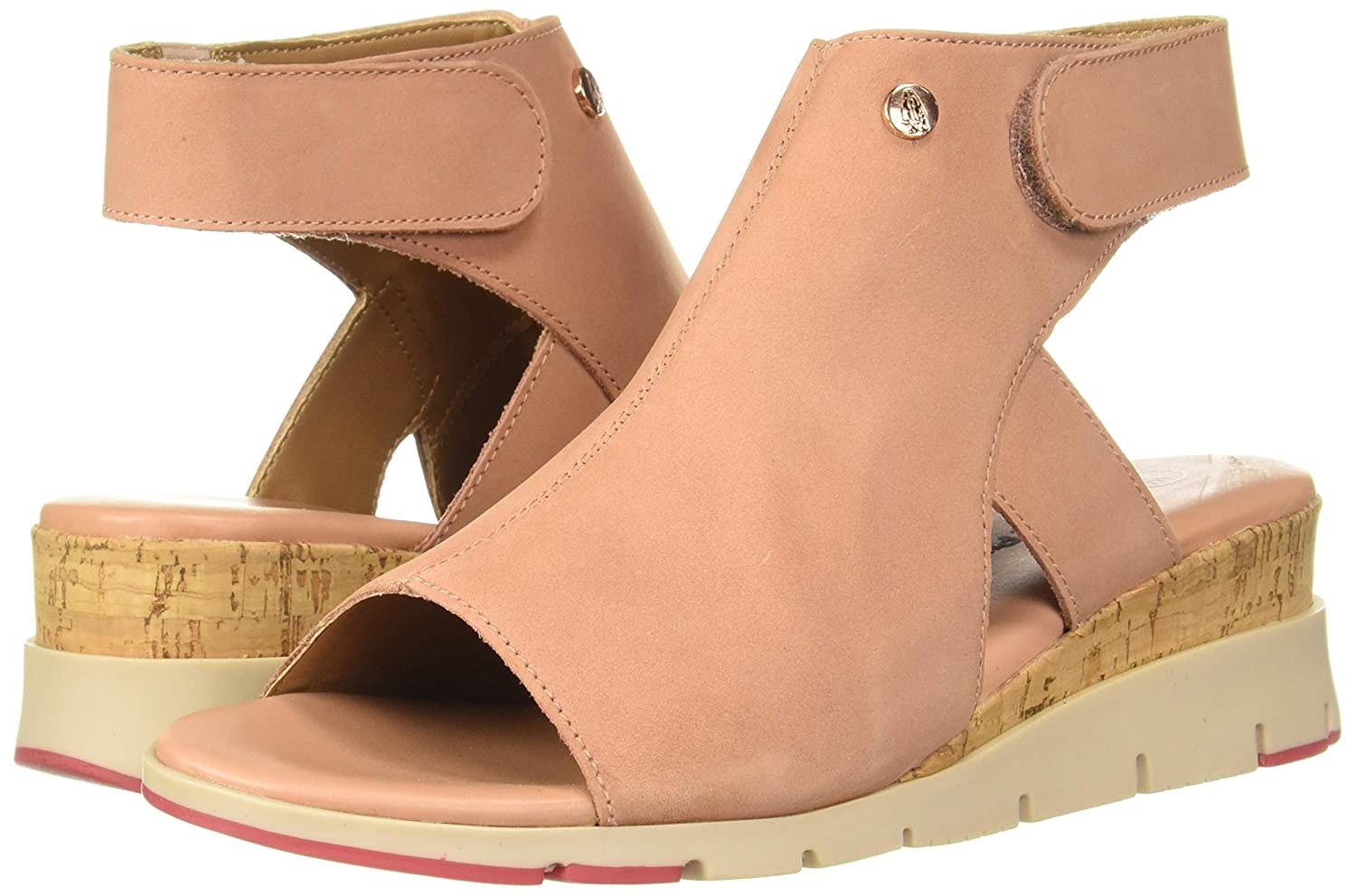 A pair of baby pink wedges with a high top strap around the ankle