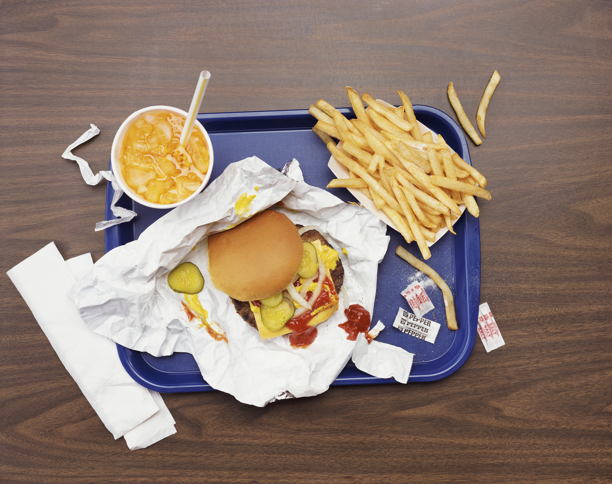 A cheeseburger, fries, and a soda on a tray