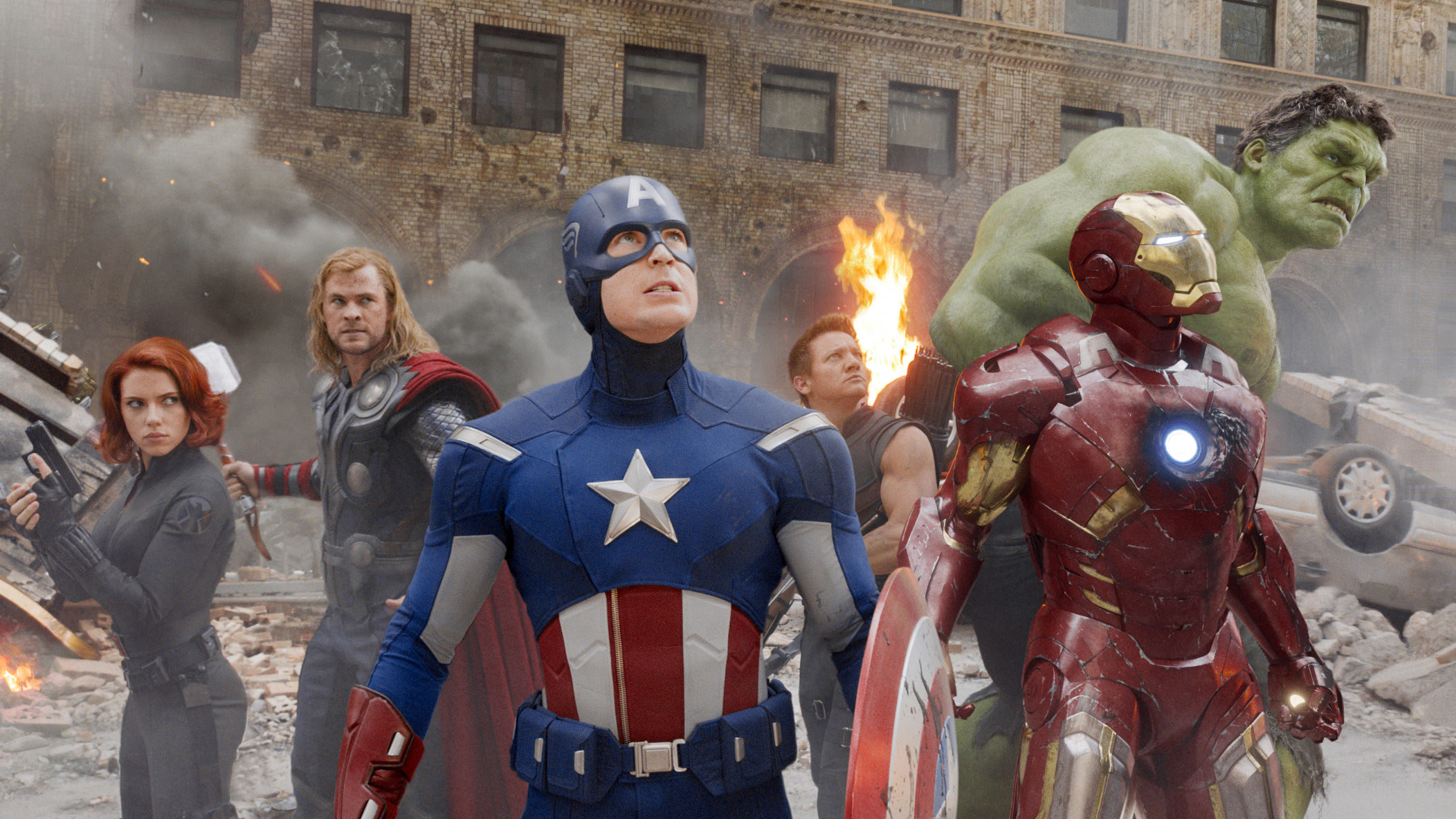 Black Widow standing with Thor, Captain America, Hawkeye, Iron Man, and the Hulk during a battle scene