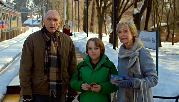 Grandpa, Grandma, and their grandson stand together at the train station