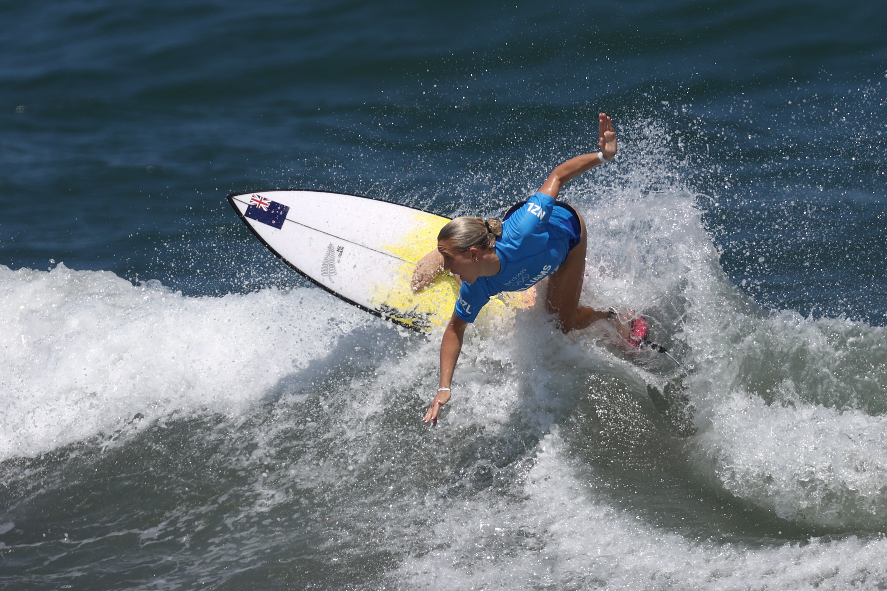 Ella surfing a wave, arms wide