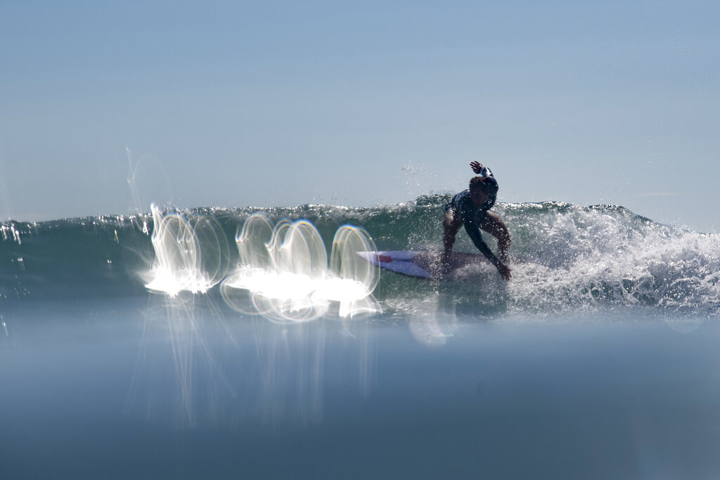 Manuel riding a wave in bright sunlight