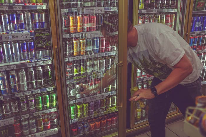 A man selecting an energy drink from a display.