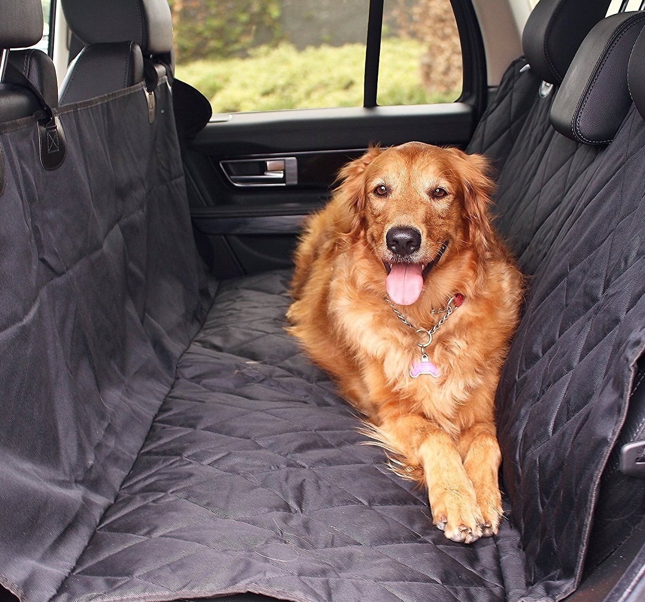 A Golden Retriever laying down in the backseat of a car with a car seat cover over the seats