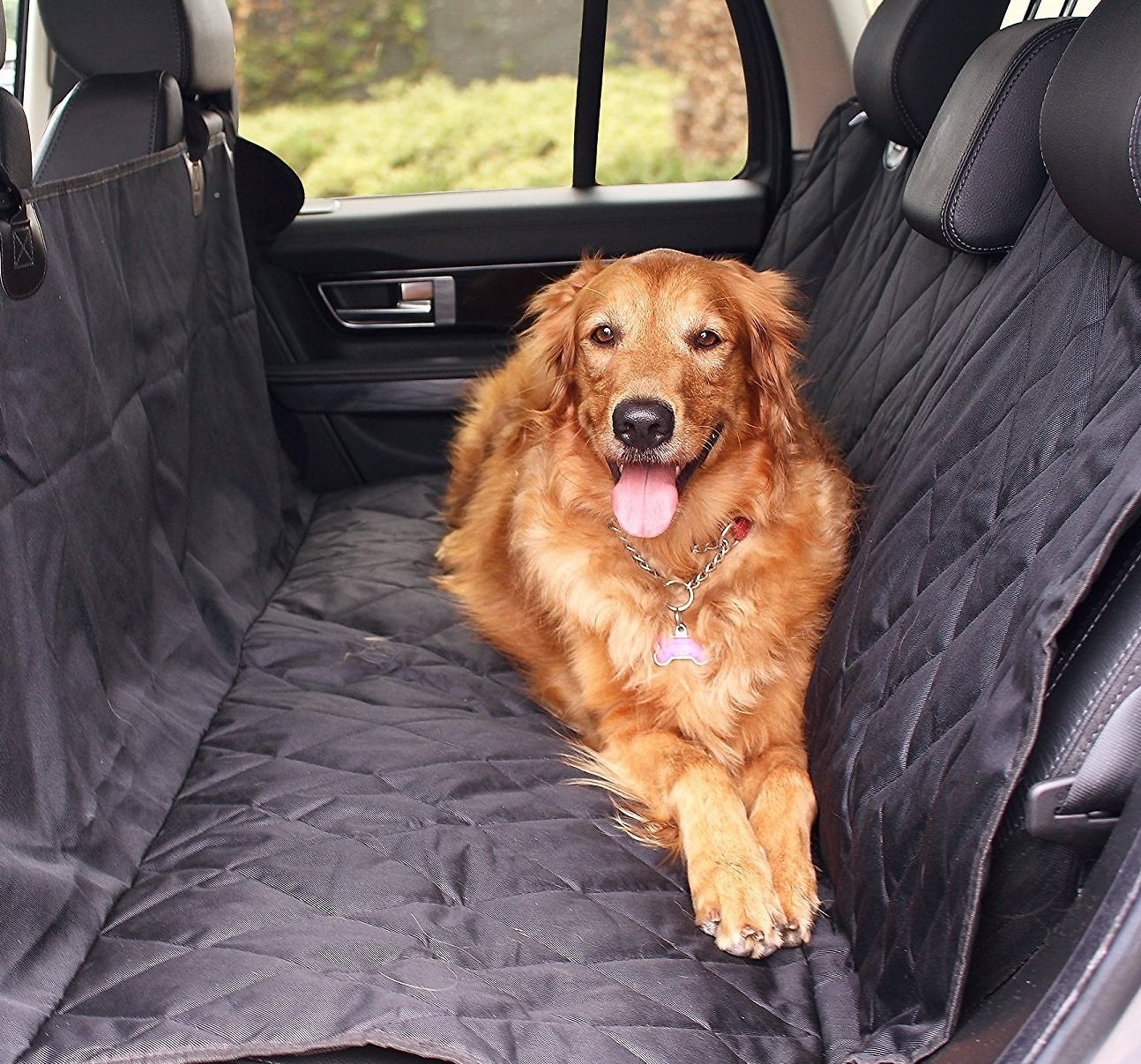 A Golden Retriever laying down in the backseat of a car with a car seat cover over the seats