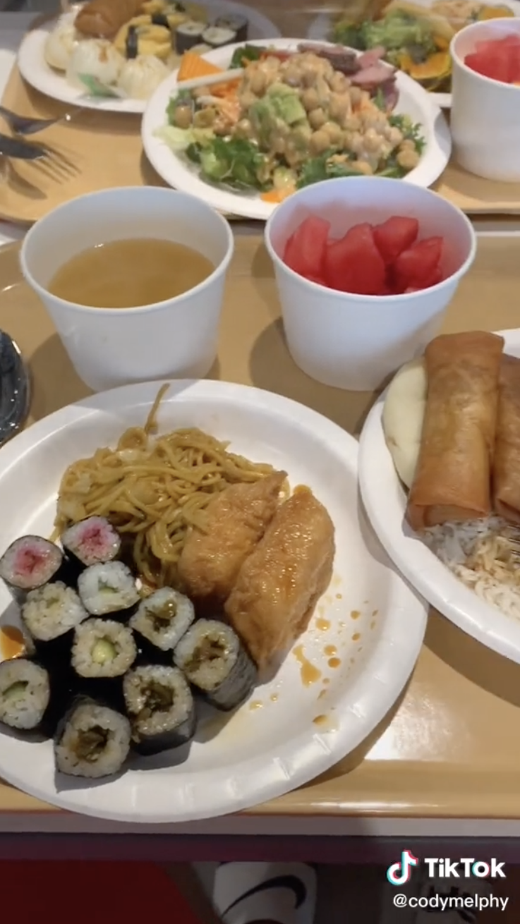 A plate filled with noodles, sushi, and egg rolls