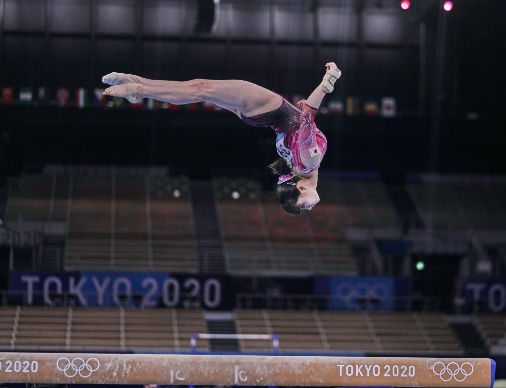 A gymnast doing a flip over the beam