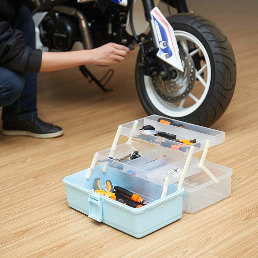 A person fixing a bike using tools from an open 3-layer tool box