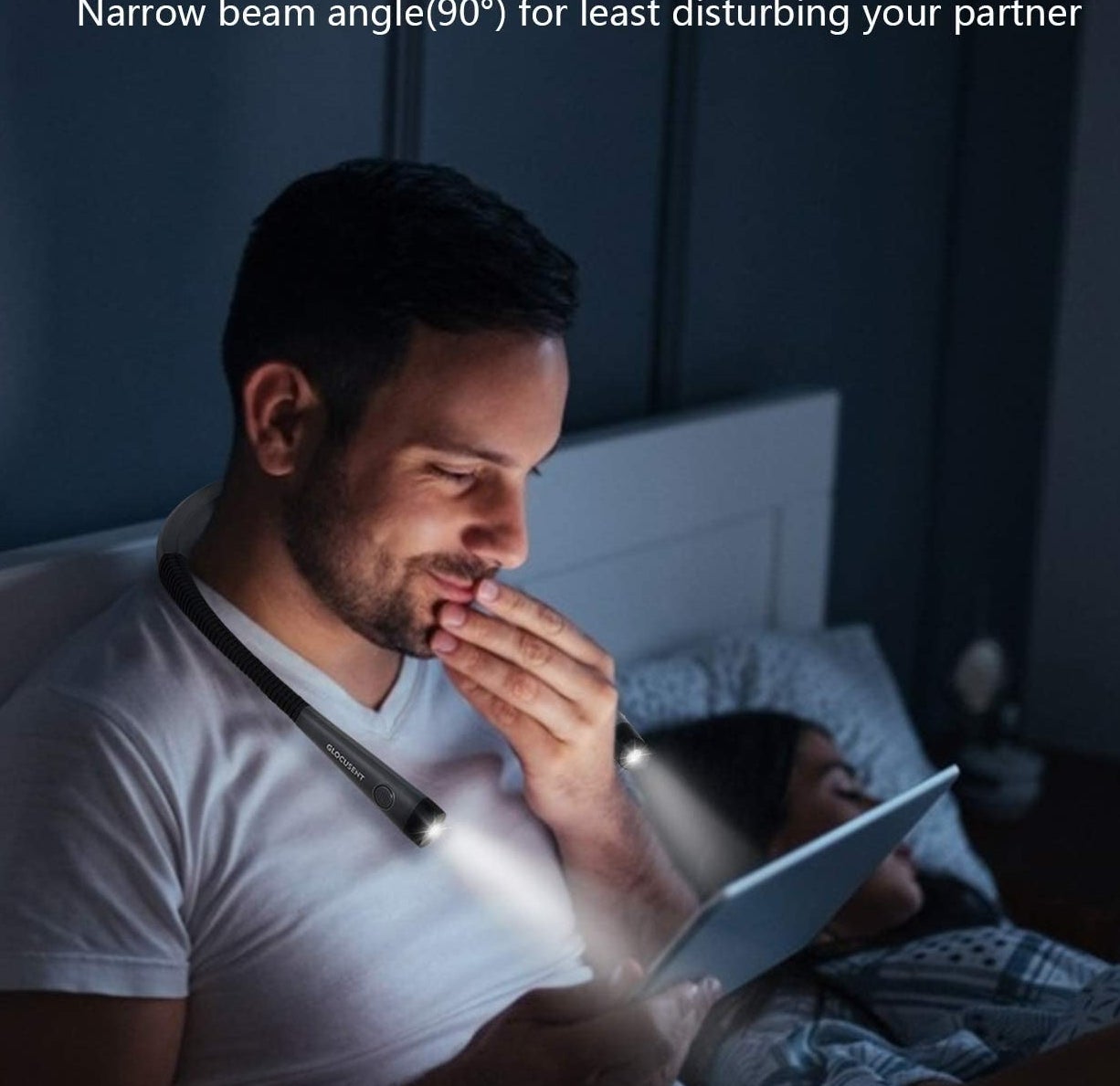 A person wearing the light while looking at their tablet in bed