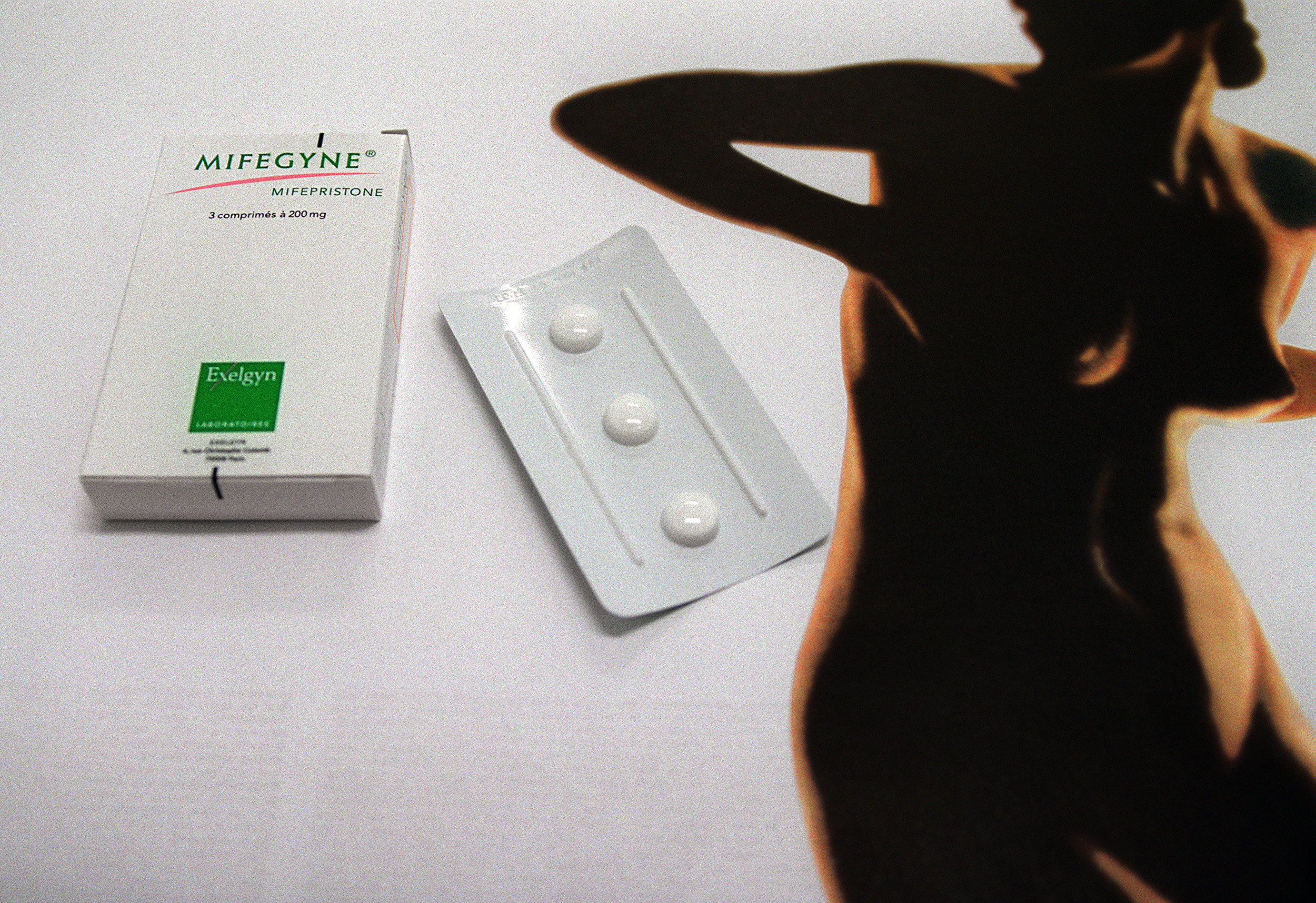 An image of the abortion pill next to the outline of a woman&#x27;s body