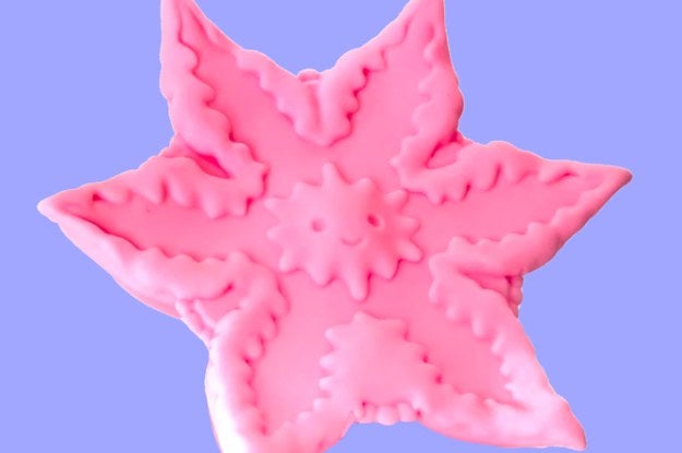 Starfish shaped toy with smiley face in center 