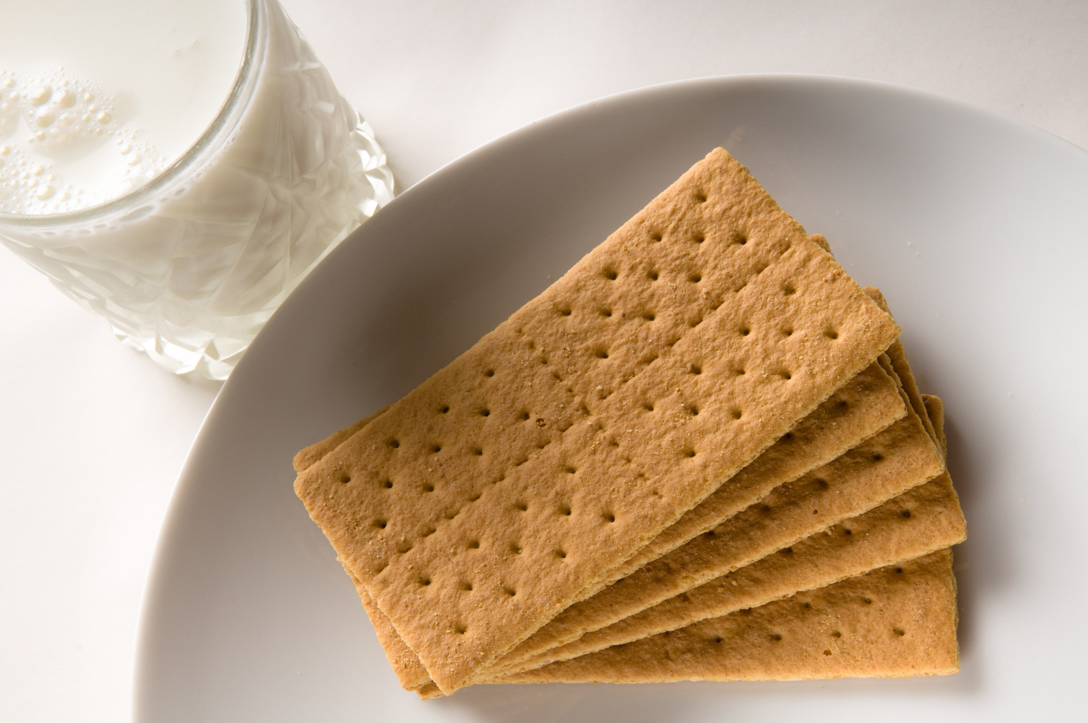 plate of graham crackers next to a glass of milk