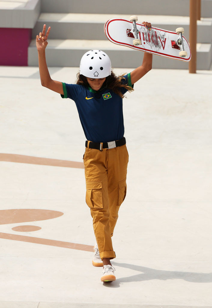 Rayssa holding her skateboard up in the air