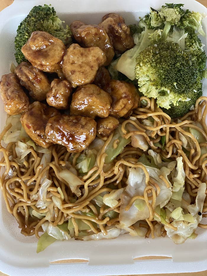Plant-based orange chicken, broccoli, and chow mein in a styrofoam container