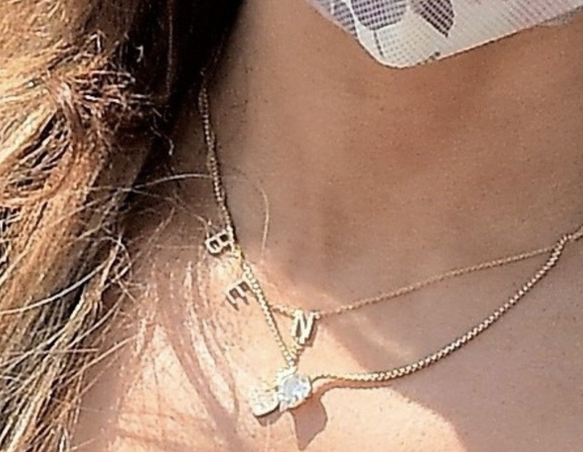 A zoom in on Jen&#x27;s jewelry where a gold necklace that says BEN can be seen