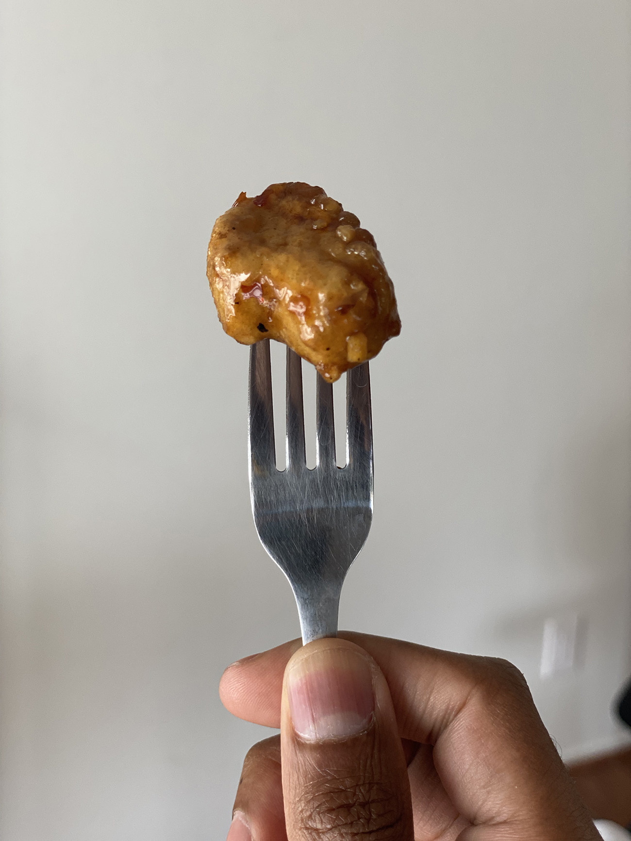 A piece of plant-based orange chicken on a fork