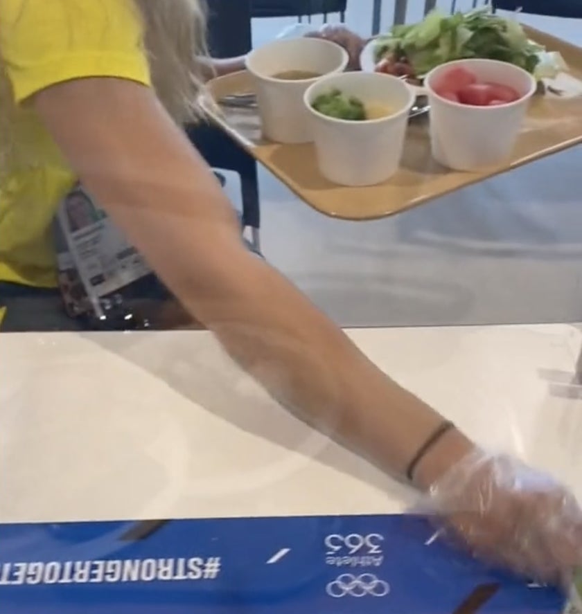An athlete wipes her table clean while wearing a glove