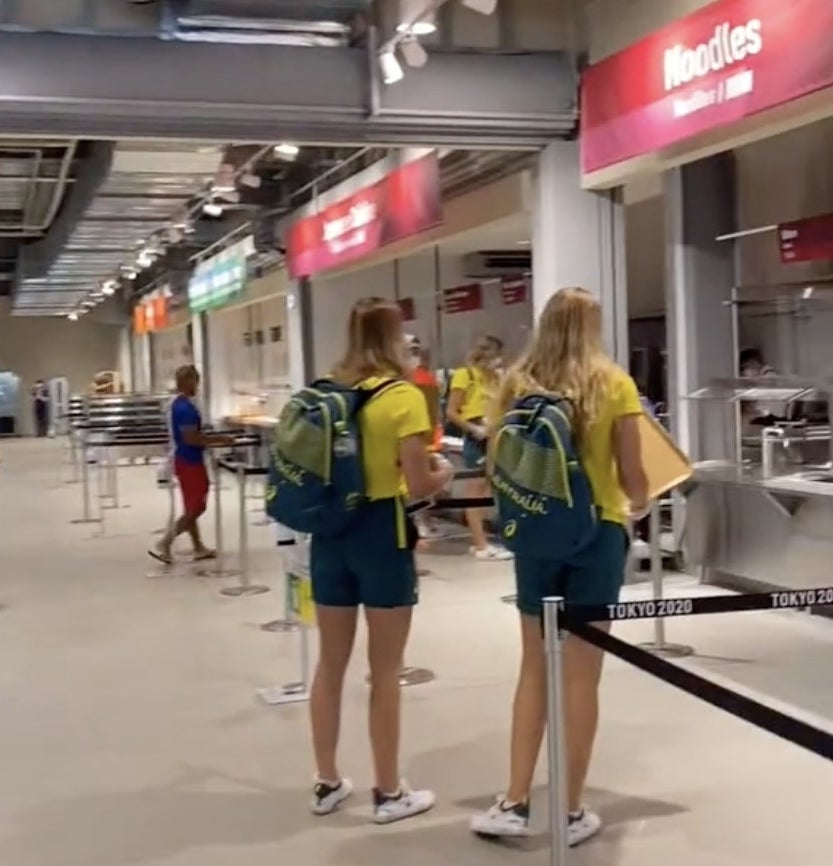 Two Team Australia members stand while waiting for their food