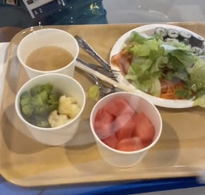 A tray filled with food including a salad, watermelon and broccoli